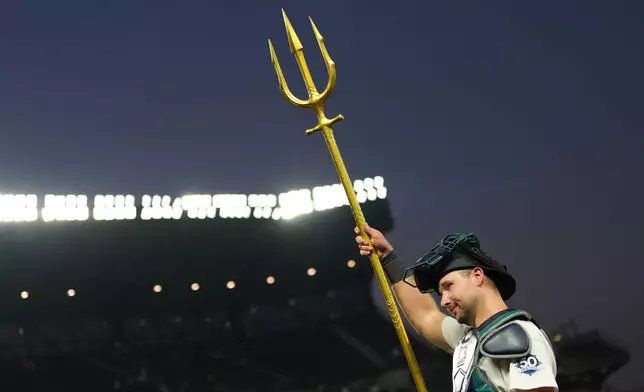 Seattle Mariners catcher Cal Raleigh lifts the trident to celebrate a win over the Cincinnati Reds in a baseball game, Monday, July 20, 2026, in Seattle. (AP Photo/Lindsey Wasson)