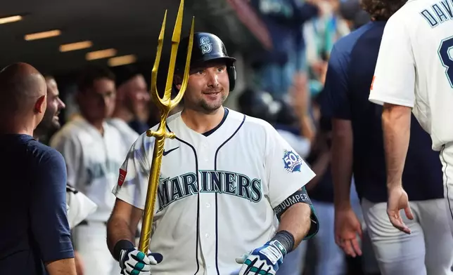 Seattle Mariners' Cal Raleigh celebrates in the dugout after hitting a grand slam against the Cincinnati Reds during the seventh inning of a baseball game, Monday, July 20, 2026, in Seattle. (AP Photo/Lindsey Wasson)