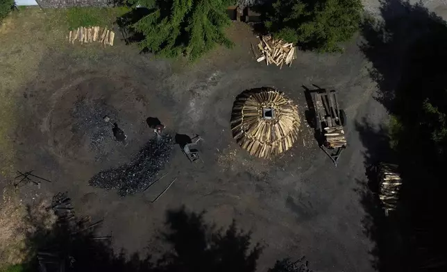 Brothers Immo and Sascha Feldmer work at their family-run, traditional charcoal production site near Hasselfelde in Germany's Harz forest, Saturday, July 11, 2026. (AP Photo/Matthias Schrader)