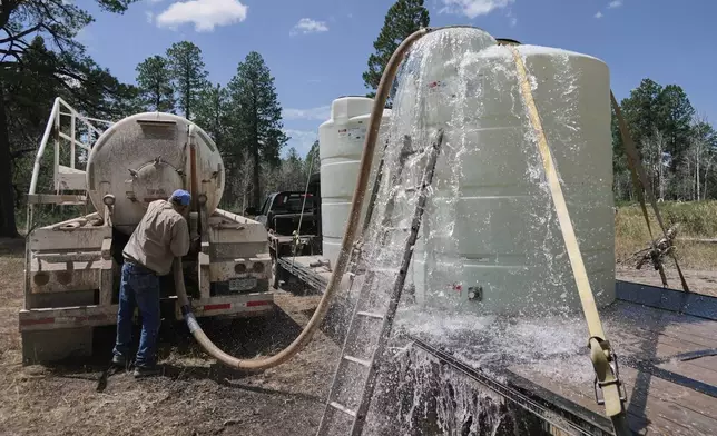 A tank overflows as Scott Snyder transfers water for his cattle, July 16, 2026 near Montrose, Colo. (AP Photo/Brittany Peterson)