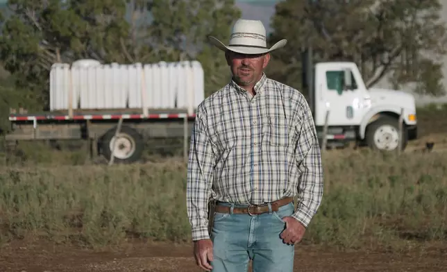Lance Bray stands in front of a truck he purchased this spring for hauling stock water, July 17, 2026 in Redvale, Colo. (AP Photo/Brittany Peterson)