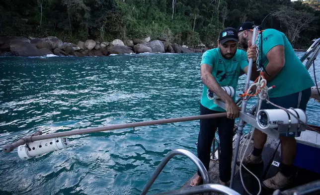 Scientific coordinator Leonardo Mitrano Neves, left, and field and logistics coordinator Daniel Shimada Brotto retrieve a Baited Remote Underwater Video System during monitoring as part of a shark project in Ilha Grande Bay, Angra dos Reis, Rio de Janeiro state, Brazil, July 14, 2026. (AP Photo/Bruna Prado)