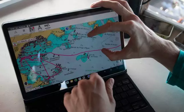 A researcher displays a tablet with a mapping system used to identify research sites for a shark project in Ilha Grande Bay, Angra dos Reis, Rio de Janeiro state, Brazil, July 14, 2026. (AP Photo/Bruna Prado)
