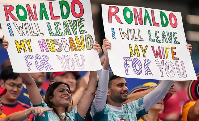 Fans hold up signs before the World Cup round of 16 soccer match between Spain and Portugal in Arlington, Texas, near Dallas, Monday, July 6, 2026. (AP Photo/Ashley Landis)