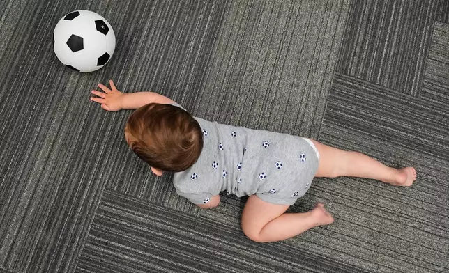 Ten-month-old Beck Ehinger plays with a soccer ball at a program introducing toddlers to the sport ahead of the World Cup soccer tournament Thursday, June 4, 2026, in Lenexa, Kan. (AP Photo/Charlie Riedel)