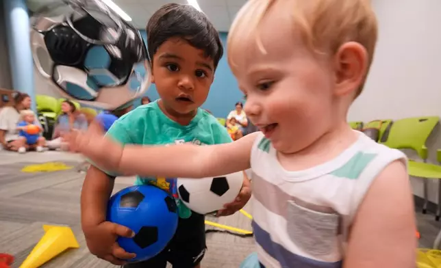 One-year-olds Ryder Greene, right, and Salaar Kahn play with a soccer balls at a program introducing toddlers to the sport ahead of the World Cup soccer tournament Thursday, June 4, 2026, in Lenexa, Kan. (AP Photo/Charlie Riedel)