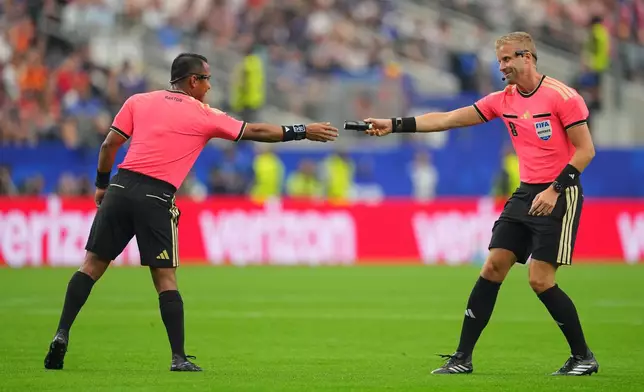 An assistant referee hands referee Ivan Barton of El Salvador the vanishing spray during a World Cup semifinal soccer match between France and Spain in Arlington, Texas, near Dallas, Tuesday, July 14, 2026. (AP Photo/Julio Cortez)