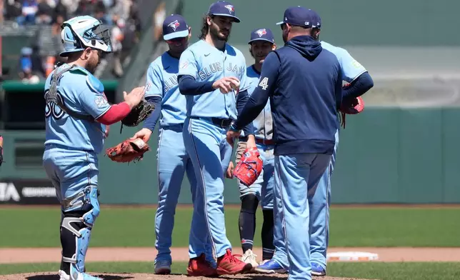 Toronto Blue Jays pitcher Dylan Cease, middle, hands the ball to manager John Schneider during a pitching change in the ninth inning of a baseball game against the San Francisco Giants Wednesday, July 8, 2026, in San Francisco. (AP Photo/Jeff Chiu)
