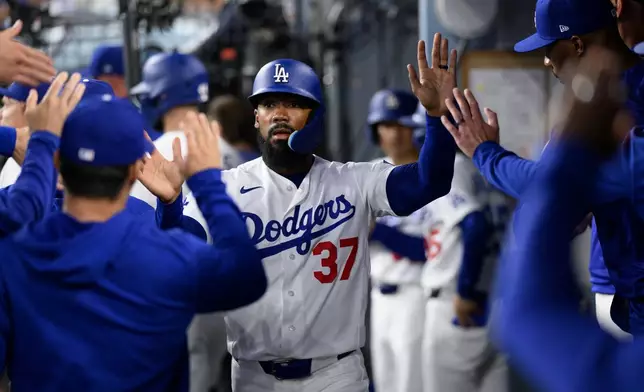 Los Angeles Dodgers' Teoscar Hernández is greeted after scoring on a sacrifice fly hit by Miguel Rojas during the fourth inning of a baseball game against the Colorado Rockies in Los Angeles, Monday, July 6, 2026. (AP Photo/Kyusung Gong)