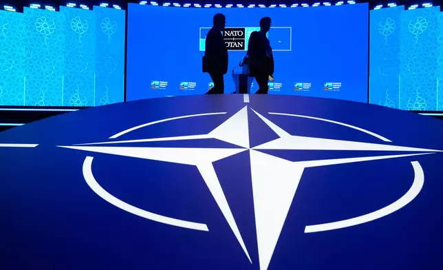 Two men walk past the NATO logo during the NATO Defense Industry Forum at the NATO summit in Ankara, Turkey, Tuesday, July 7, 2026. (AP Photo/Hussein Malla)
