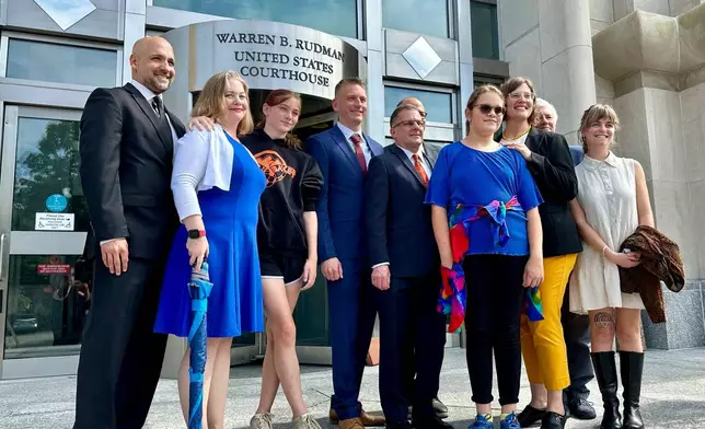 FILE - Two teens challenging New Hampshire's new law banning transgender girls from girls' sports teams, Parker Tirrell, third from left, and Iris Turmelle, sixth from left, pose with their families and attorneys in Concord, N.H., Aug. 19, 2024. (AP Photo/Holly Ramer, File)