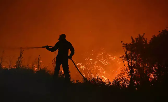 A firefighter works on a wildfire on the outskirts of the northern city of Thessaloniki, Greece, Sunday, July 5, 2026. (AP Photo/Giannis Papanikos)