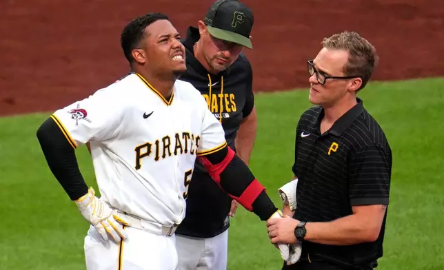 Pittsburgh Pirates manager Don Kelly, center, watches as Esmerlyn Valdez, left, is examined by a team trainer, right, after being hit by a pitch from Arizona Diamondbacks' Merrill Kelly during the fourth inning of a baseball game in Pittsburgh, Monday, July 27, 2026. (AP Photo/Gene J. Puskar)