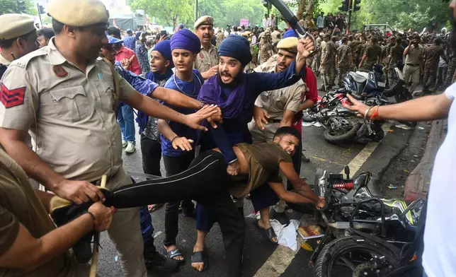 Supporters of the Cockroach Janta Party scuffle with police as they attempt to march toward India's Parliament, demanding the resignation of the education minister, in New Delhi, Monday, July 20, 2026. (AP Photo/Vipin)