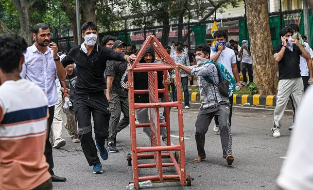 Supporters of the Cockroach Janta Party remove a police barricade as they attempt to march toward India's Parliament, demanding the resignation of the education minister, in New Delhi, India, Monday, July 20, 2026. (AP Photo/Prakash Singh)