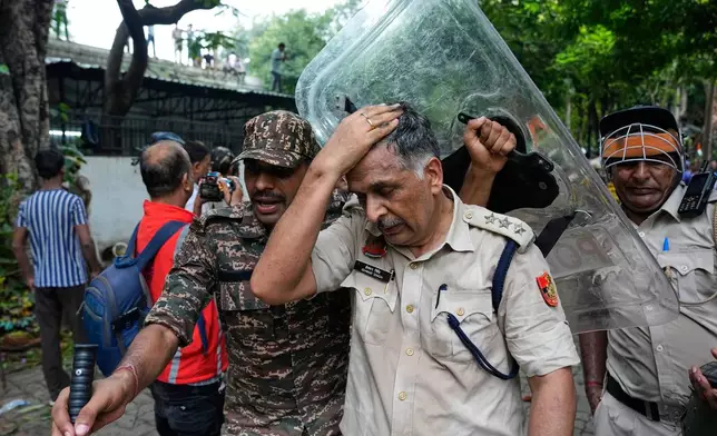 An injured police officer is taken for treatment after being hurt during clashes with supporters of the Cockroach Janta Party attempting to march toward India's Parliament in New Delhi, India, Monday, July 20, 2026. (AP Photo/Manish Swarup)