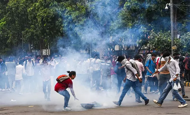 Supporters of the Cockroach Janta Party try to neutralize a tear gas shell fired by police as they attempt to march toward India's Parliament, demanding the resignation of the education minister, in New Delhi, India, Monday, July 20, 2026. (AP Photo/Prakash Singh)