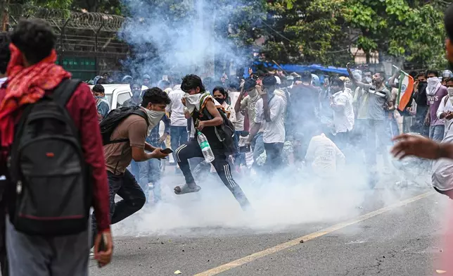 Supporters of the Cockroach Janta Party try to neutralize a tear gas shell fired by police as they attempt to march toward India's Parliament, demanding the resignation of the education minister, in New Delhi, India, Monday, July 20, 2026. (AP Photo/Prakash Singh)