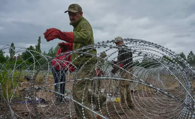 Ukrainian workers install barbed wire close to the Ukraine-Belarus border in an undisclosed location in Ukraine Tuesday, July 7, 2026. (AP Photo/Efrem Lukatsky)