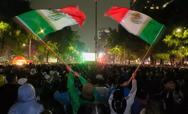 Mexican fans wave flags as they watch the World Cup round of 32 soccer match between Mexico and Ecuador near the Angel of Independence monument in Mexico City, Tuesday, June 30, 2026. (AP Photo/Marco Ugarte)