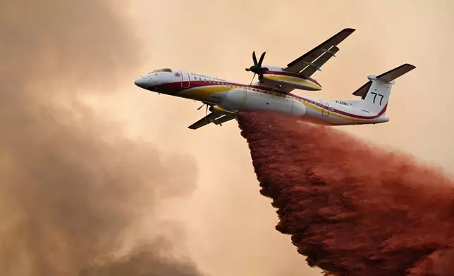 A De Havilland Canada Dash 8-400 drops fire retardant over a forest near Saint-Jean-d'Illac, during wildfires in southwestern France, Tuesday, July 28, 2026. (AP Photo/Emma Da Silva)