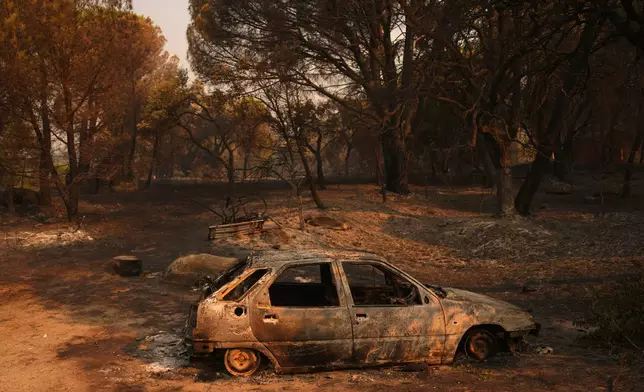 A car burned by a wildfire sits in Piedralaves, Ávila province, Spain, as the fire continues to spread, Tuesday, July 28, 2026. (AP Photo/Manu Fernandez)