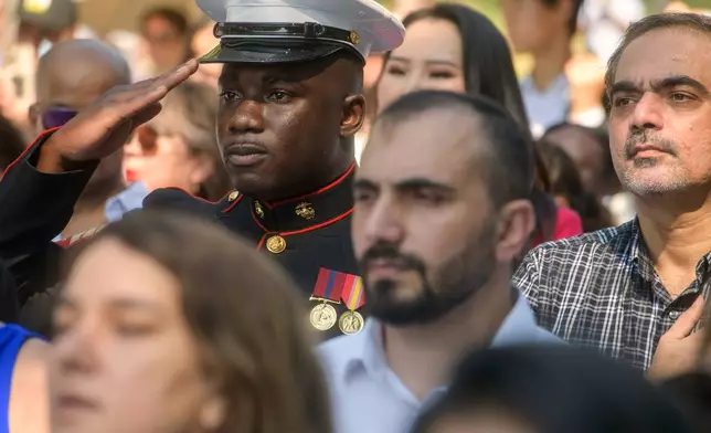 U.S. Marine Sgt. Diakaria Sangare, center, from Guinea, salutes the playing of the national anthem at a naturalization ceremony on Independence Day at George Washington's Mount Vernon, Saturday, July 4, 2026, in Alexandria, Va. (AP Photo/Rod Lamkey, Jr.)