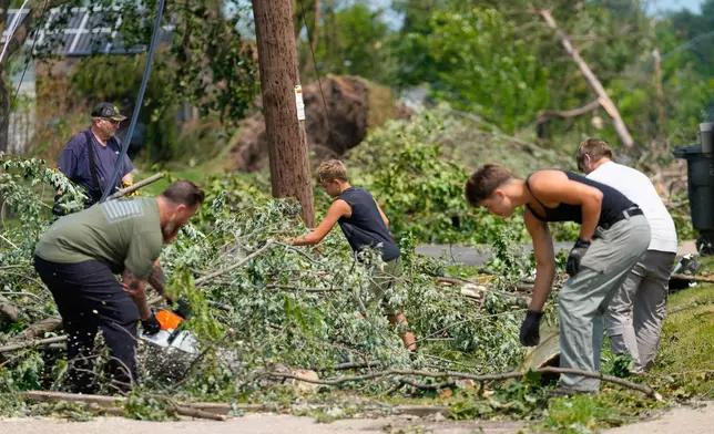 Volunteers help clear tree limbs near a damaged house after a tornado hit the day before in Appleton, Wis., Tuesday, July 28, 2026. (AP Photo/Kayla Wolf)