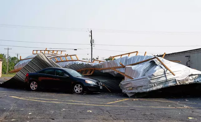 A car sits in a parking lot under a collapsed roof after a tornado struck the day before, Tuesday, July 28, 2026, in Appleton, Wis. (AP Photo/Kayla Wolf)