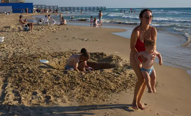 A family enjoys the Mediterranean Sea in Rishon LeZion, Tuesday, June 23, 2026. The beach is located near a military firing range that had been used for decades and is slated to be cleared and opened for public use. (AP Photo/Ariel Schalit)