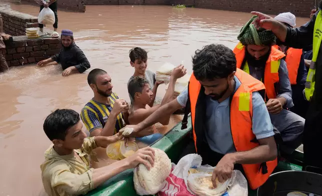 Rescue worker provides food to flood victims at a flooded area near Lahore, Pakistan, Monday, Jun 27, 2026. (AP Photo/K.M. Chaudary)