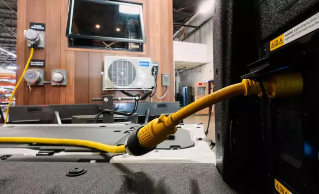 A one-foot long adapter is shown connected to a 240-volt outlet onboard a Ford F-150 King Ranch on Wednesday, July 22, 2026, in Southgate, Mich. The adapter makes the vehicle compatible to plug into a longer, separate cable that connects to a transfer switch installed directly on one's electric meter. (AP Photo/Paul Sancya)
