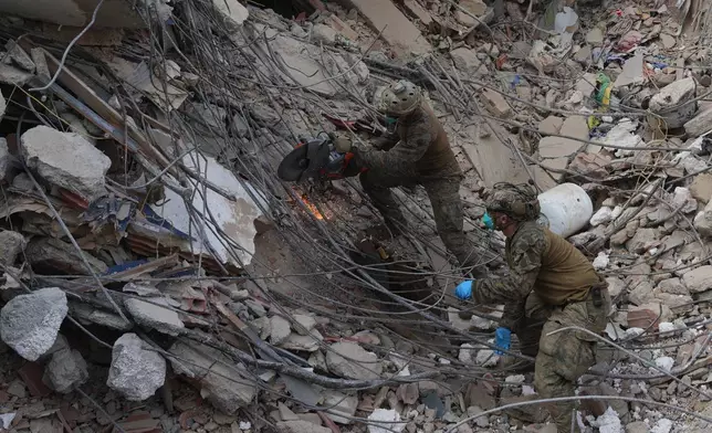 U.S. troops cut through rebar while clearing rubble during a search at a building that collapsed in the twin earthquakes in La Guaira, Venezuela, Tuesday, June 30, 2026. (AP Photo/Ariana Cubillos)