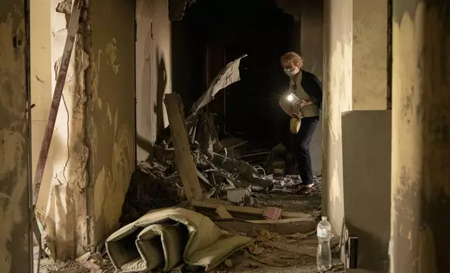 A woman using a mobile phone light inspects her apartment damaged by Monday's Russian missile attack in Kyiv, Ukraine, Tuesday, July 7, 2026. (AP Photo/Dan Bashakov)