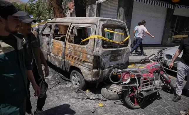 Syrian security personnel inspect a burned vehicles near the Four Seasons Hotel after two explosions rocked the area earlier while Syrian President Ahmad al-Sharaa was meeting French President Emmanuel Macron at the presidential palace, in Damascus, Syria, Tuesday, July 7, 2026. (AP Photo/Omar Albam)