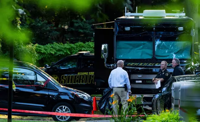 Law enforcement officials investigate the scene of a fatal house fire on Friday, July 24, 2026, in Grand Haven Township, Mich. (Joel Bissell/Kalamazoo Gazette via AP)