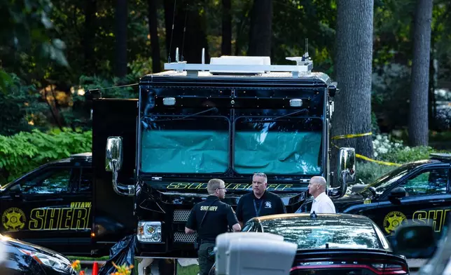 Law enforcement officials gather to investigate a fatal house fire on Friday, July 24, 2026, in Grand Haven Township, Mich. Ottawa County Sheriff's Office said six children and two adults were found dead in a "suspicious" house fire. (Joel Bissell/Kalamazoo Gazette via AP)