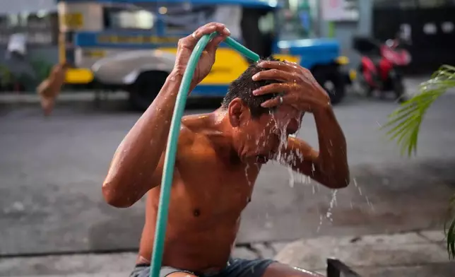 Jeepney driver Edgar Funelas bathes outside along a street near the jeepney where he and his 10-year-old daughter live in Quezon City, Philippines, on Friday April 10, 2026. (AP Photo/Aaron Favila)