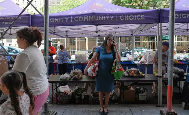 Marlyn Garcia collects food from the West Side Campaign Against Hunger's food distribution center in New York on Tuesday, June 30. (AP Photo/Mary Conlon)