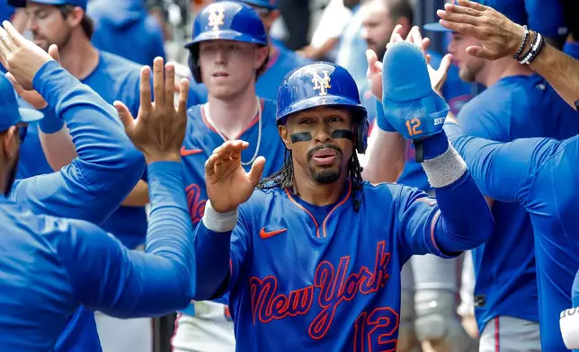 New York Mets' Francisco Lindor (12) and Brett Baty, behind, are greeted in the dugout after they scored against the Atlanta Braves during the second inning of a baseball game, Sunday, July 5, 2026, in Atlanta. (AP Photo/Erik S. Lesser)