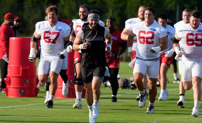 Tampa Bay Buccaneers quarterback Baker Mayfield, black shirt, laughs as he runs with the offensive linemen during an NFL football training camp practice Wednesday, July 29, 2026, in Tampa, Fla. (AP Photo/Chris O'Meara)