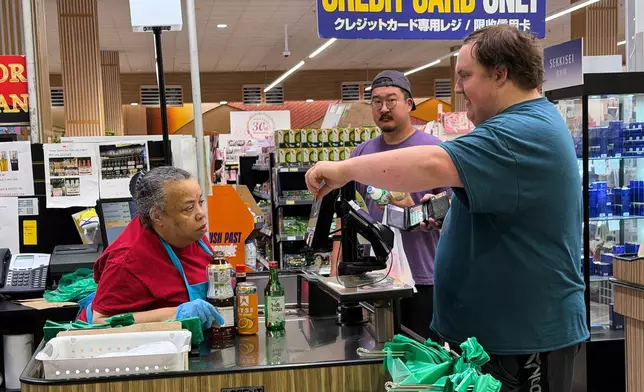 An employee checks a customer's identification card before checking out alcohol at a cash register in a grocery store in Arlington Heights, Ill., Monday, July 6, 2026. (AP Photo/Nam Y. Huh)