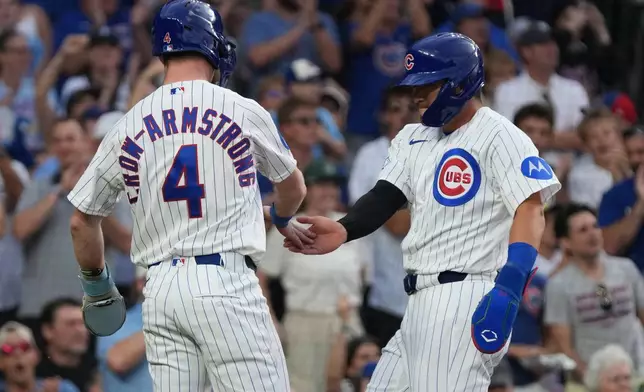 Chicago Cubs' Pete Crow-Armstrong, left, greets Seiya Suzuki, right, after they scored against the Detroit Tigers during the first inning of a baseball game Tuesday, July 21, 2026, in Chicago. (AP Photo/David Banks)