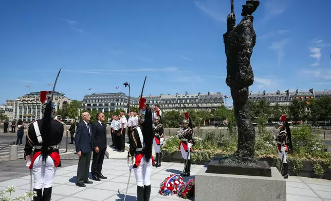 France's President Emmanuel Macron, center right, with Charles Dreyfus grandson of Alfred Dreyfus during a tribute ceremony to Captain Alfred Dreyfus on the first national day dedicated to the recognition of his innocence by the Court of Cassation in 1906, and the fight against the resurgence of antisemitism, 120 years later, on the Ile de la Cite near the Cour de Cassation in Paris, Sunday, July 12, 2026. (Thomas Samson/Pool Photo via AP)
