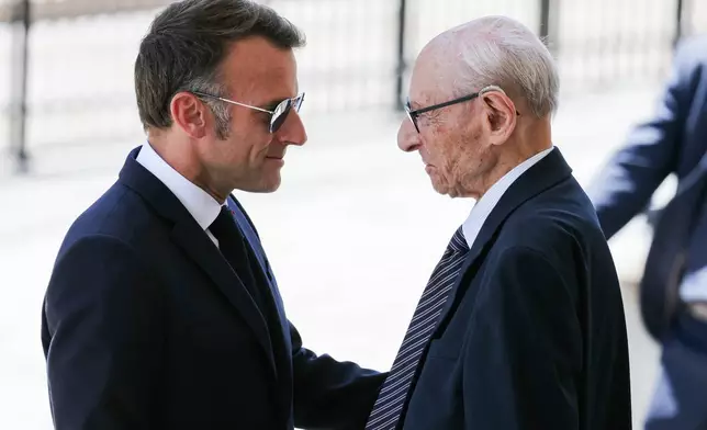 France's President Emmanuel Macron, left, with Charles Dreyfus grandson of Alfred Dreyfus during a tribute ceremony to Captain Alfred Dreyfus on the first national day dedicated to the recognition of his innocence by the Court of Cassation in 1906, and the fight against the resurgence of antisemitism, 120 years later, on the Ile de la Cite near the Cour de Cassation in Paris, Sunday, July 12, 2026. (Thomas Samson/Pool Photo via AP)