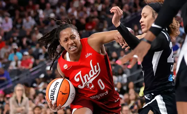 Indiana Fever guard Kelsey Mitchell (0) drives against Las Vegas Aces guard Chennedy Carter (23) during the first half of an WNBA basketball game Sunday, July 5, 2026, in Las Vegas. (Steve Marcus/Las Vegas Sun via AP)