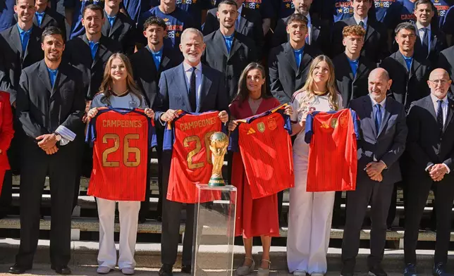 Spain's King Felipe VI and Queen Letizia, accompanied by Princess Leonor, left, and Infanta Sofia, right, pose with players from Spain's national soccer team at Zarzuela Palace in Madrid on Monday, July 20, 2026, after the team was crowned World Cup champion. (Jose Oliva/Europa Press via AP)