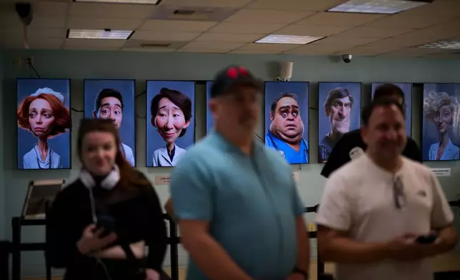 Visitors listen to an introduction before touring the "Hospital of Emotions" exhibition as displays depicting health care workers are seen in the background inside a former hospital building in Los Angeles, Wednesday, July 22, 2026. (AP Photo/Jae C. Hong)