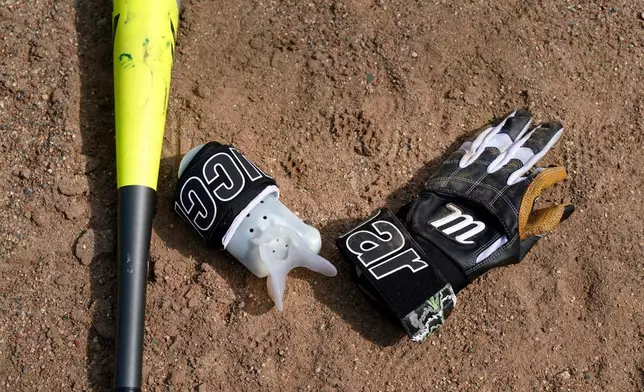A bat, glove and a device to allow Brittany Apgar, who was born without a right hand, to hold a bat are shown at a field in Greensboro, N.C., Wednesday, July 22, 2026. (AP Photo/Chuck Burton)