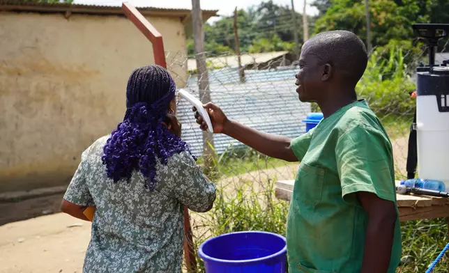 A health worker checks the temperature of a woman at the ebola treatment centre in Bunia, Congo, Monday, July 20, 2026. (AP Photo/Prosper Heri Ngorora)